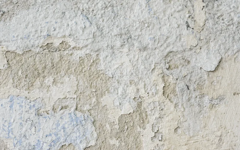 Flaking, failed coating on a stucco wall
