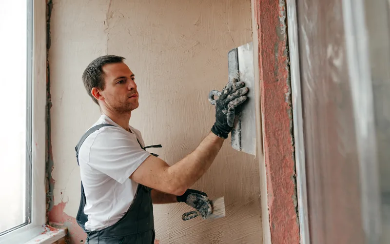 Plastering an interior wall around a window in an occupied room